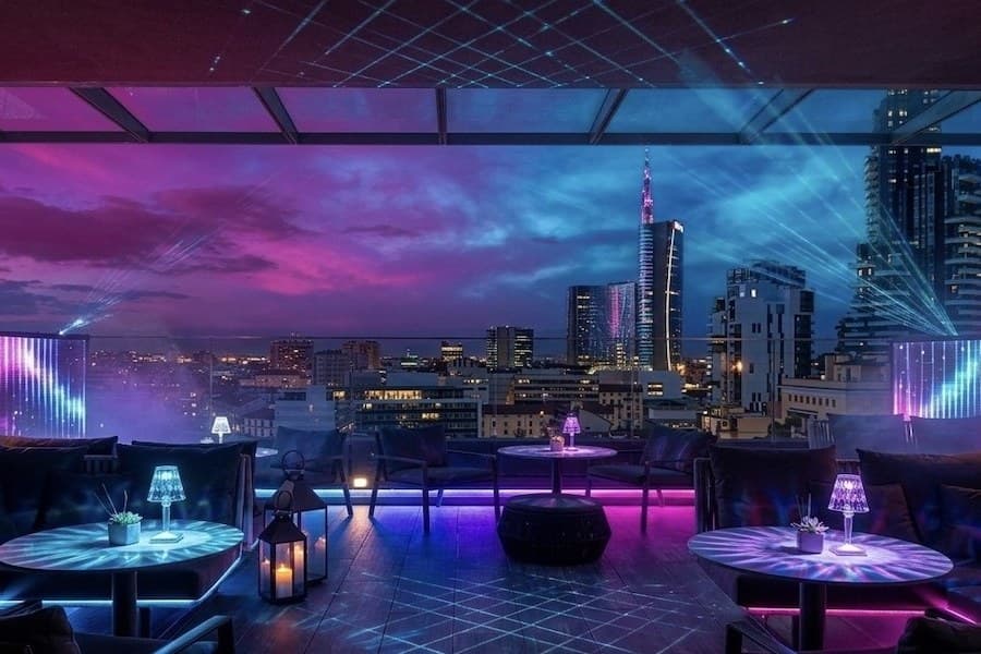 Una terrazza panoramica allestita la sera, con lo skyline di Milano sullo sfondo.